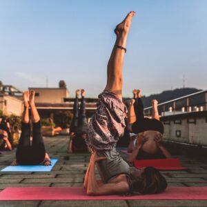 People practicing yoga on mats outdoors during sunset, focusing on wellness.