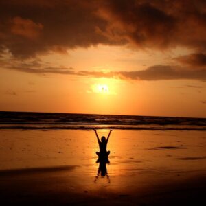 Peaceful meditation silhouette at sunset on a serene beach.